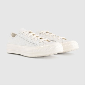 Converse Chuck 70 low-top trainers in vintage white leather with perforated toe cap, white laces, and cream rubber cupsole.