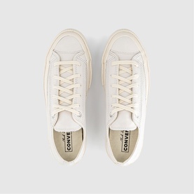 Converse low-top trainers in vintage white, leather upper with lace-up fastening, cream rubber sole, overhead flat-lay view