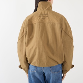 Model wearing Acne Logo Technical Bomber Jacket in dark khaki, back view showing embroidered logo detail, styled with blue jeans.