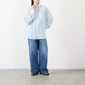 Model wearing Acne blue lyocell oversized shirt, styled with wide-leg mid-wash jeans and black loafers
