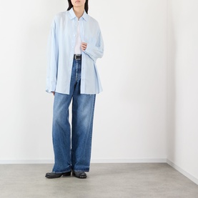 Model wearing Acne 1981 U Vintage Wide-Leg Jeans in mid blue with whiskering, styled with a pale blue oversized shirt and black loafers.