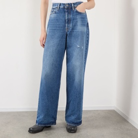 Model wearing Acne 1981 U Vintage Wide-Leg Jeans in mid blue with whiskering, wide leg, and clean hems, styled with black leather shoes.