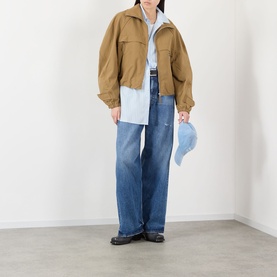 Model wearing Acne 1981 U Vintage Wide-Leg Jeans in Mid Blue with tan cropped jacket, blue shirt, and black loafers