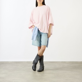 Model wearing Acne white oversized cotton T-shirt, styled with light blue denim shorts and dark grey cowboy boots.