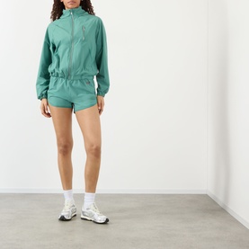 Model wearing Adanola Eucalyptus Green zip-up windbreaker jacket, styled with matching shorts and white trainers.