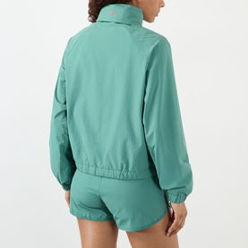 Model wearing Adanola Eucalyptus Green jacket, rear view, shown with matching green shorts. Elasticated hem and cuffs, zip-up style.