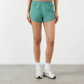Model wearing Adanola Eucalyptus Green shorts, styled with white ankle socks and chunky trainers.