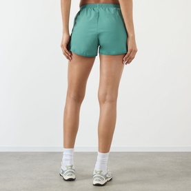 Model wearing Adanola Eucalyptus Green shorts, rear view, styled with white ankle socks and chunky trainers.
