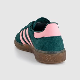 Adidas trainer in collegiate green suede with pink three stripes, pink heel tab, and gum rubber sole, rear angle view.