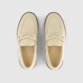 Cream leather penny loafers, top-down view showing saddle strap detail and brown rubber sole edge