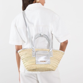 Model carrying Jacquemus Le Petite Panier Soli Basket Bag in silver, woven palm leaf with metallic panels, silver top handles and crossbody strap