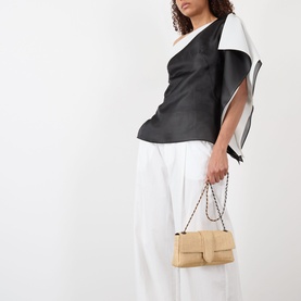 Model carrying Jacquemus Le Bambino Chaine Shoulder Bag in natural woven leather with silver-toned hardware and twisted chain strap, styled with