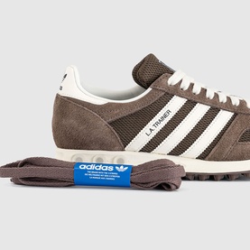 Adidas L.A. Trainer in earth strata brown and off-white suede with three white stripes, cream sole, and spare laces.
