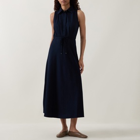 Model wearing Luisa Cerano Dark Blue Denim Shirt Dress, sleeveless midi with pointed collar and tie belt, styled with flat mules.