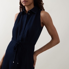 Model wearing Luisa Cerano Dark Blue Denim Shirt Dress, sleeveless midi with pointed collar, concealed buttons and tie belt at waist.