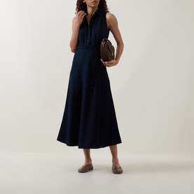 Model wearing Luisa Cerano Dark Blue Denim Shirt Dress; midi length, sleeveless, tie waist. Styled with tan loafers and a brown bag.