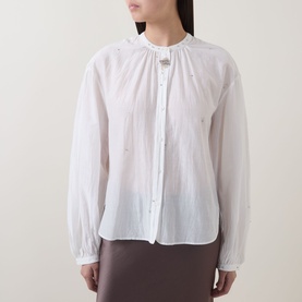 Model wearing Luisa Cerano off white cotton-silk shirt with ruffled neckline, button front, and blouson sleeves, styled with a taupe skirt.