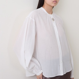 Model wearing Luisa Cerano off white cotton-silk shirt with puffed sleeves, elasticated cuffs, and band collar with button fastening.
