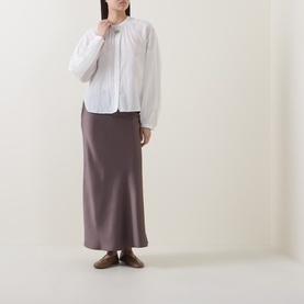 Model wearing Luisa Cerano Off White cotton-silk shirt with gathered neckline, styled with a mauve satin midi skirt and brown loafers.