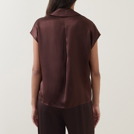 Model wearing Luisa Cerano dark brown silk shirt, rear view showing centre back pleat detail and cap sleeves, styled with matching trousers.