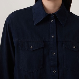 Model wearing Luisa Cerano Blouson Denim Blouse in dark blue, featuring snap button placket and two chest flap pockets with snap fastenings