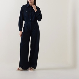 Model wearing Luisa Cerano Blouson Denim Blouse in dark blue with wide-leg trousers and beige sandals.