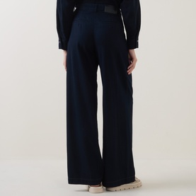 Model wearing Luisa Cerano dark blue wide-leg cotton trousers with black belt, styled with black top and beige chunky sole shoes, rear view