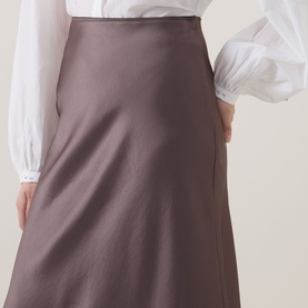Model wearing Luisa Cerano olive satin midi skirt with A-line silhouette, styled with a white puff-sleeve blouse