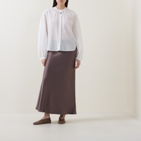 Model wearing Luisa Cerano olive satin midi skirt with white blouse and flat mules