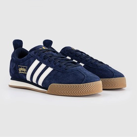 Adidas trainers in Night Indigo and Chalk White, suede upper with three white stripes, gold branding, and tan gum rubber sole.