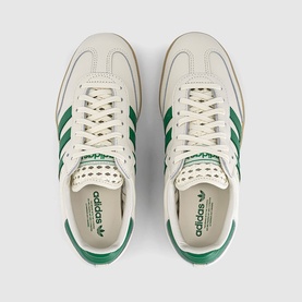 Adidas trainers in off-white with green three-stripe detailing, green laces, and gum sole, shown from above as a pair.