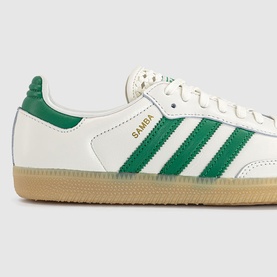 Adidas Samba trainers in off-white leather with green three-stripe detailing, gold branding, and gum rubber sole.