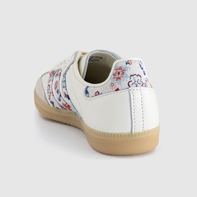 Adidas trainer in off-white with Liberty floral print detailing on heel and side stripe, gum rubber sole, rear three-quarter view.