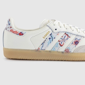 Adidas Samba trainers in off-white with Liberty floral print three stripes, gold branding, white laces, and gum sole.