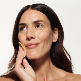 Model with Skin Rocks The Strong Acid toner pad held to cheek, demonstrating application technique