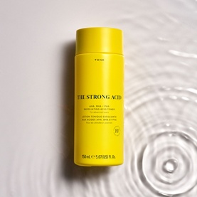Skin Rocks The Strong Acid exfoliating toner in bright yellow bottle, 150ml, shown on wet rippled surface