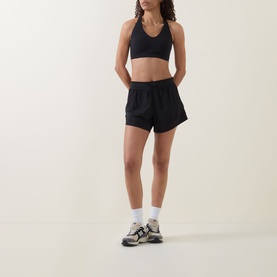 Model wearing black running shorts with black sports bra, white ankle socks and grey trainers