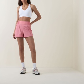 Model wearing Sweaty Betty Dove White sports bra with pink athletic shorts and white trainers