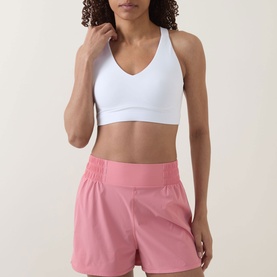 Model wearing Sweaty Betty Dove White sports bra with V-neck and racerback, styled with pink athletic shorts