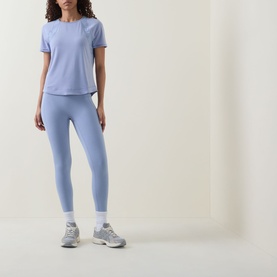 Model wearing Sweaty Betty leggings in Laguna Blue Marl, styled with matching blue tee, white socks and grey trainers.