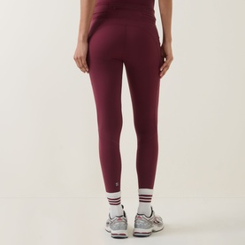 Model wearing Sweaty Betty Merlot Red leggings, shown from behind, styled with striped socks and grey trainers