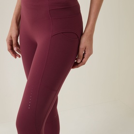 Model wearing Sweaty Betty leggings in Merlot Red, featuring high waist, side pocket, and small logo detail at hem.