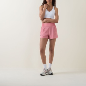 Model wearing Sweaty Betty melrose pink shorts, styled with white vest top, white socks and chunky trainers