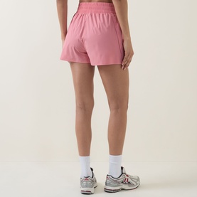 Model wearing Sweaty Betty melrose pink shorts, styled with white ankle socks and grey trainers, back view