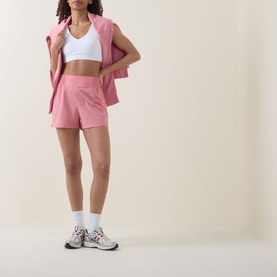 Model wearing Sweaty Betty melrose pink shorts with matching zip-up vest, white sports bra, ankle socks and silver trainers.