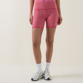 Model wearing Sweaty Betty shorts in Red Micro Stripe Print, styled with white ankle socks and grey trainers