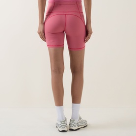 Model wearing Sweaty Betty shorts in Red Micro Stripe Print, rear view, styled with white socks and grey trainers.