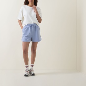 Model wearing light blue drawstring shorts with white oversized T-shirt, patterned ankle socks, and chunky trainers