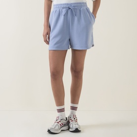 Model wearing light blue drawstring sweat shorts, styled with white ankle socks and grey trainers