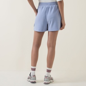 Model wearing light blue pull-on shorts with elasticated waist, styled with white ankle socks and grey trainers, rear view
